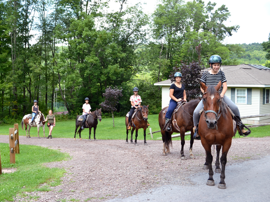 A group of campers on horseback wearing helmets.