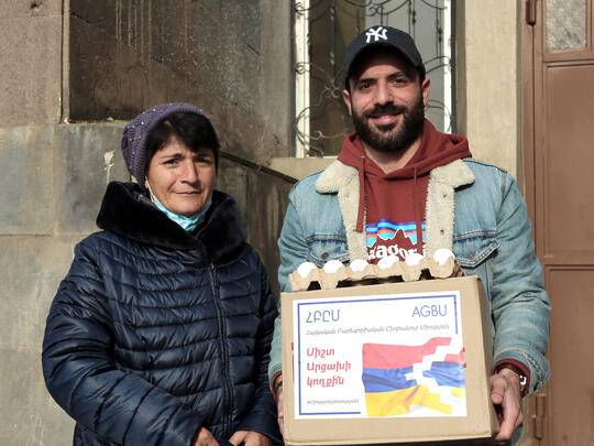 Volunteer distributing food box to a woman from Artsakh