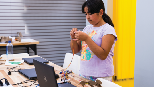 Young girl with black hair working on computer.